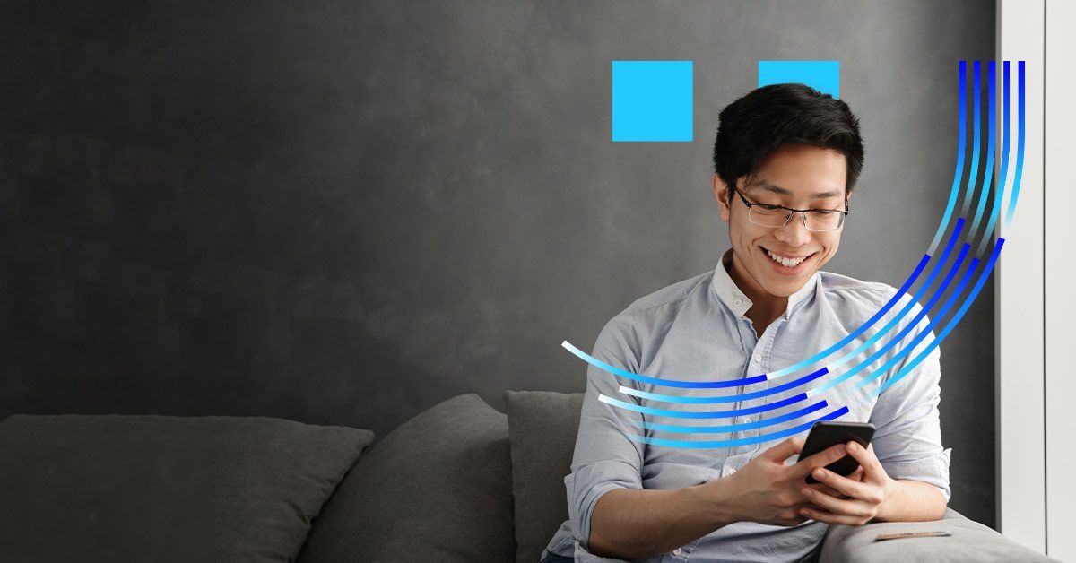 A man smiling while using his mobile phone