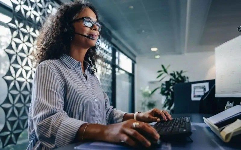 Shot of a woman using a headset and computer in a modern office