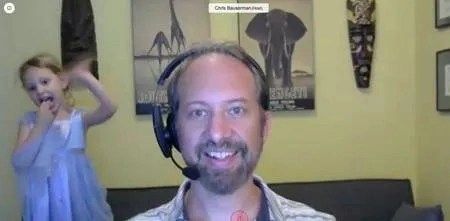 Chris Bauserman conducts a video conference call from home and his daughter says hello in the background. 