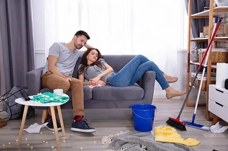 homebased couple relax on a sofa while tidying up
