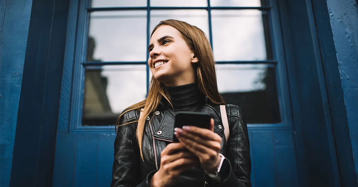 Woman on her phone, excited with the launch of NiCE New World