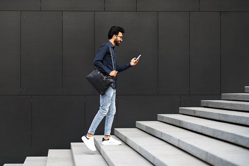 Man at staircase using his phone to check the new NiCE world