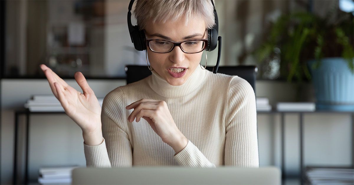 Woman sitting at desk in headphones consult client on laptop online